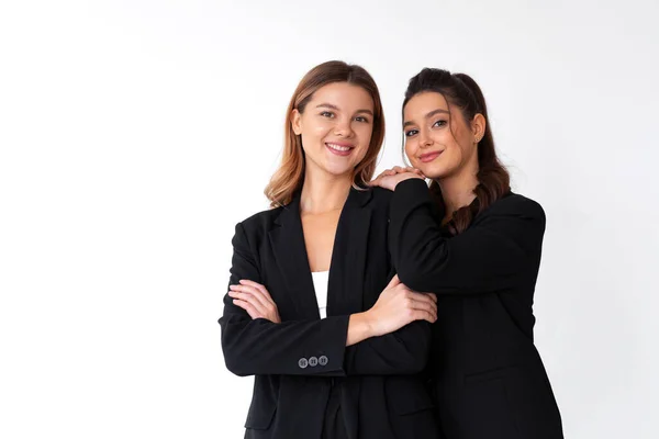 ビジネスにおけるパートナーシップの概念 2人の若い実業家が黒の正式なスーツスタジオ独立した白い背景を着ていた ブルネットの女性は彼女の友人の肩に手を置きます — ストック写真