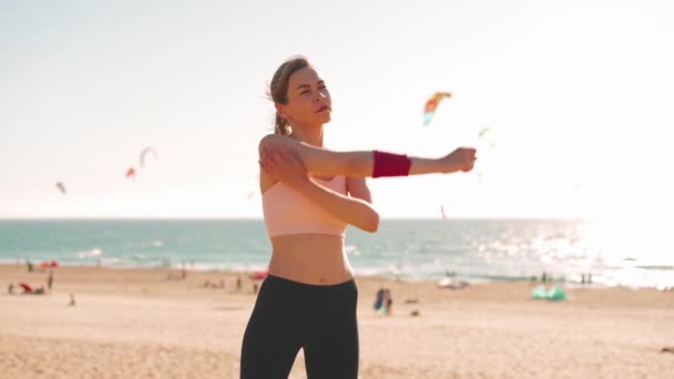 柔韧的高加索女孩在紧张的跑步训练后伸出手来 运动女性中年在户外运动前热身 夏天穿着运动衫在海滨穿衣 — 图库视频影像