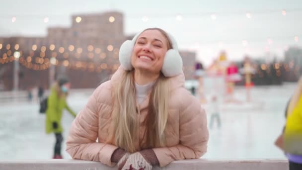 幸せな女性アイスリンク屋外で時間を過ごす クリスマス休暇 毛皮の耳フスケートアイススケートの女性は 中央市の広場にオープンシティアイスリンクスケート 冬のアクティブなレジャー 35歳女性 — ストック動画