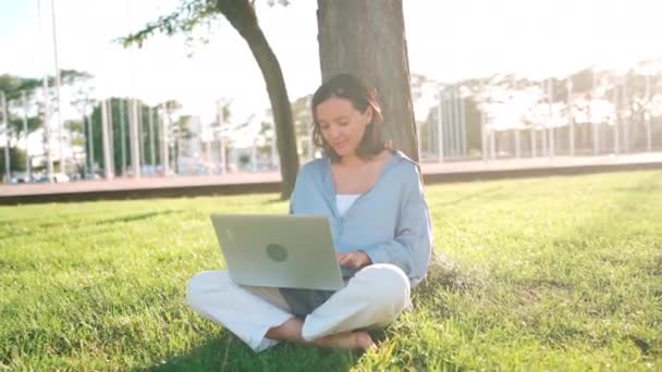 Szczęśliwa Brunetka Korzystająca Laptopa Siedząc Przy Drzewie Trawie Parku Młoda — Wideo stockowe