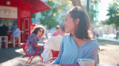 Garsonu arıyorum. Genç ve güzel bir kadın, yemek ve kahve faturalarını ödemek için garsonu arıyor. Kafkasyalı bayan açık hava kafeteryasında güneş ışığı altında yaz günü oturuyor. Orta ölçekli. Yetişkin kız menüye sor