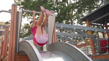 Çocuk sıcak yaz gününde oyun parkında oynuyor. Küçük kız eğleniyor. Mutlu bir çocukluk. Kafkasyalı küçük kız 5 yıldır açık havada oynuyor.