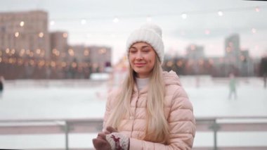 Kış zamanı. Winter City caddesinde kışın giyinmiş ve beyaz örülü şapka takmış mutlu yetişkin bir kadın. Beyaz, kadın, kışın açık havada. Noel tatili kavramı. Neşeli gülümseyen kişi. Kış günü