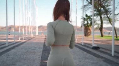 Following Shot of Young Woman in Sportswear Confidently Running through Summer Park near Seaside. Back View Athletic Female Jogger run at morning workout training