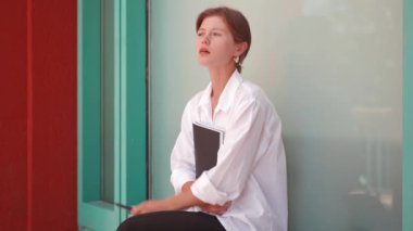 Businesswoman smoking e-cigarette. Caucasian frustrated female business person sad sitting street lost her job has financial problems smoking electronic cigarette. lonely female woman stress at work