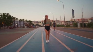 Kadın koşmadan önce kollarını esnetiyor ve ısınıyor. Formda sporcu bir kadın ısınmak için koşu pistinde koşuya hazırlanıyor. Atletik kadın antrenmana hazırlan.