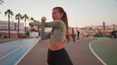 Koşu parkurunda koşmadan önce esneme ve ısınma hareketleri. Formda sporcu kadın vücudunu ısıtıyor. Yaz akşamları spor giyinen kız dışarıda egzersiz yapıyor. 