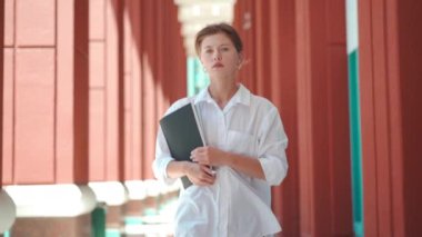 İş kadını başarılı kadın iş adamı açık havada şirket binası dış görünüşü heyecan verici Kafkasyalı kendine güvenen profesyonel iş kadını klasör belgelerini ağır çekimde tutuyor.. 