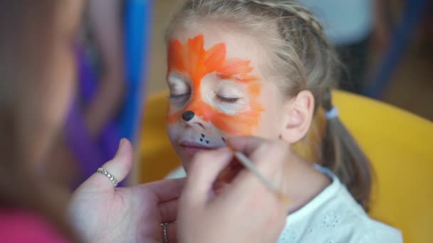 孩子们面对绘画 在孩子们的嘉年华会上 艺术家们在小女孩的脸上涂上了夸张而特殊的虎形面具 儿童的身体艺术绘画 — 图库视频影像