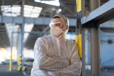 COVID-19 Coronavirus doktoru hastane otoparkında beyaz koruyucu tulum giymişti. Bulaşıcı hastalıklar, salgın hastalık. Erkek sağlık çalışanı orta boy çekim