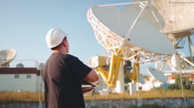 Engineer testing earth based astronomical radio telescope use laptop. Radio telescopes used in science for space observation and distant objects exploring. Big satellite dishes