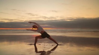Gün batımında okyanus manzaralı yoga egzersizleri. Kafkasyalı formda bir kadın deniz kıyısında yoga eğitimi alıyor. Sağlıklı yaşam tarzı kavramı. Yetişkin bir kadın yoga ve esneklik eğitimi alıyor.. 