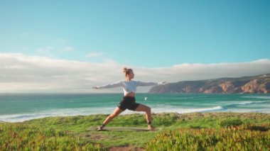 Arka planda okyanus manzaralı yoga egzersizleri. Kafkasyalı formda bir kadın deniz kıyısında yoga eğitimi alıyor. Sağlıklı yaşam tarzı kavramı. Yetişkin bir kadın yoga ve esneklik eğitimi alıyor.. 