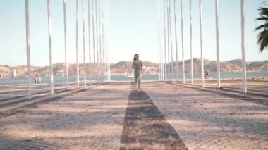 Spor Giyim 'de Genç Kadın' ın Deniz kenarındaki Yaz Parkı 'nda koşarken çekilmiş görüntüleri. Front View atletik bayan koşucu sabah antrenmanında şehir parkında deniz kenarında koşuyor.