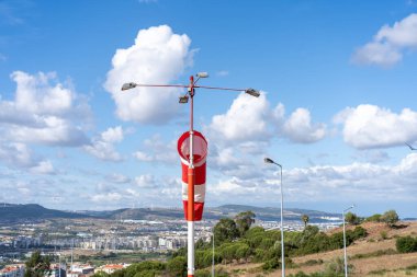 Rüzgar çorap sineği. Sıcak bir yaz günü, terk edilmiş rüzgârlı bir hava alanında, rüzgâr esiyor ve rüzgârlık tembellik ediyor. Rüzgâr Sock bulutlu gökyüzü dağı ve arka planda arabalı yol