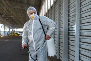 Koruyucu giysi giyen işçiler dezenfekte ekipmanları halka açık bir yerde park ediyorlar. Genel olarak dezenfektan güvenliği ve solunum maskesi Covid salgını önleyici tedbirler