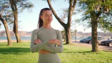 Spor kadını yaz parkında her sabah antrenman yaparken kameraya bakıp gülümseyerek kalp şeklini gösteriyor. Aktif yaşam tarzı konsepti. Spor giysili beyaz kadın koşuya hazır..