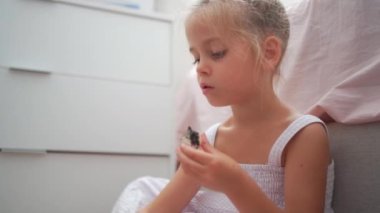 Caucasian child girl is painting watercolor paint on small ceramic figure with fun. Kids arts and crafts creative activity class at home. Little girl make ceramic decor sitting floor 