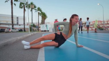 Uzun boylu, formda bir kız spor giyimi antrenman tahtası, koşu pistinde bir gece, motive olmuş gibi görünen mükemmel bir kalas egzersizi, konsantre pilates egzersizi. Sağlık, spor faaliyetleri