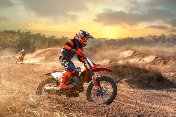 Günbatımı arka planında motosiklet süren Enduro motorcusu. Yarışmaya hazırlanıyorum. Motosiklet eğitimi. Sıra dışı motosiklet