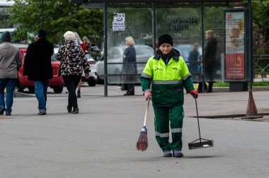 Saint Petersburg, Rusya - 10 Eylül 2021 Yaşlı bir kadın caddeyi temizliyor. Tahıl, gürültü