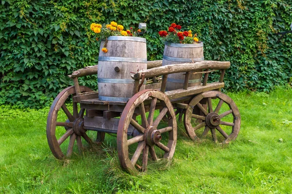 Barris de madeira com flores florescendo em um carrinho velho — Fotografia de Stock