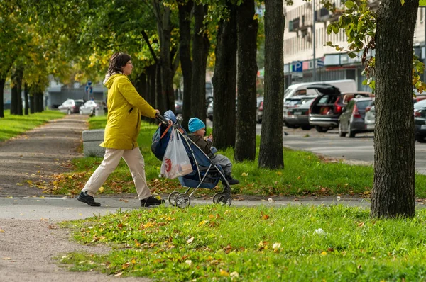 Una donna porta un bambino in un passeggino in un giorno d'autunno — Foto Stock