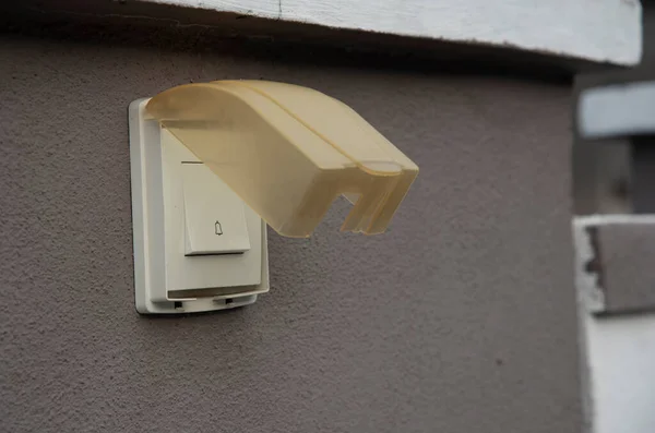 plastic doorbell switch by the entrance wall.