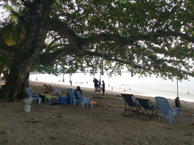 Perak, Malezya - Kasım 12021: Teluk Batik Tatil Köyü 'ndeki egzotik plajda dinlenen insanların eğlence faaliyetleri.