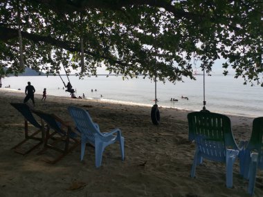 Perak, Malezya - Kasım 12021: Teluk Batik Tatil Köyü 'ndeki egzotik plajda dinlenen insanların eğlence faaliyetleri.