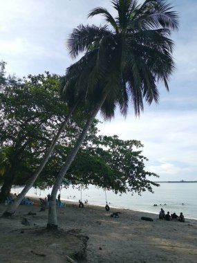 Perak, Malezya - Kasım 12021: Teluk Batik Tatil Köyü 'ndeki egzotik plajda dinlenen insanların eğlence faaliyetleri.