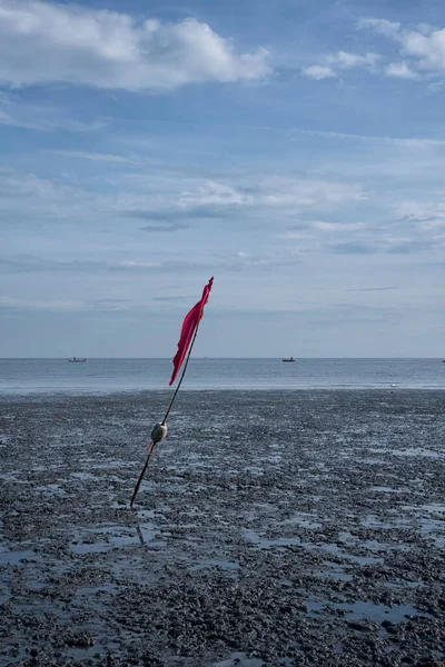 沼の海水浴場で低潮を示す赤い竹の旗竿 — ストック写真