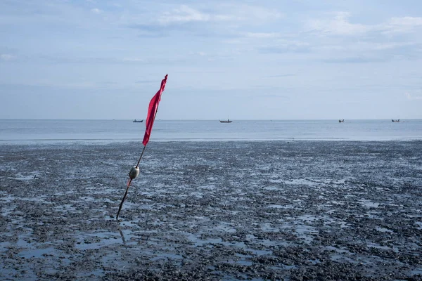 沼の海水浴場で低潮を示す赤い竹の旗竿 — ストック写真