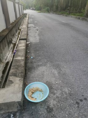 Evsiz hayvanları beslemek için yol kenarındaki açık mavi plastik kase..