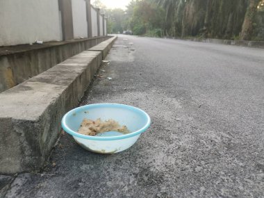 Evsiz hayvanları beslemek için yol kenarındaki açık mavi plastik kase..