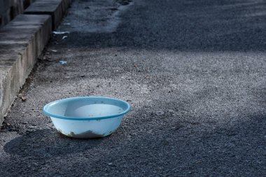 Evsiz hayvanları beslemek için yol kenarındaki açık mavi plastik kase..