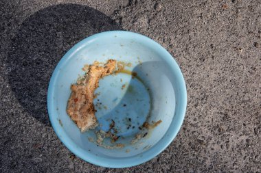 Evsiz hayvanları beslemek için yol kenarındaki açık mavi plastik kase..