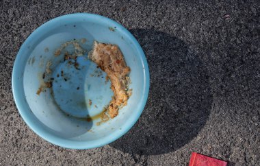 Evsiz hayvanları beslemek için yol kenarındaki açık mavi plastik kase..