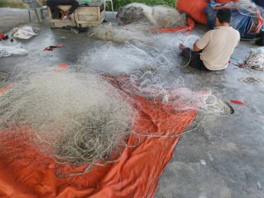 Perak, Malezya. 26 Mayıs 2022: Balıkçıların Kg Pasir Panjang, Kg Koh limanındaki balıkçı ağlarını örme veya onarma faaliyetleri.