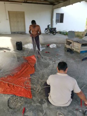 Perak, Malezya. 26 Mayıs 2022: Balıkçıların Kg Pasir Panjang, Kg Koh limanındaki balıkçı ağlarını örme veya onarma faaliyetleri.