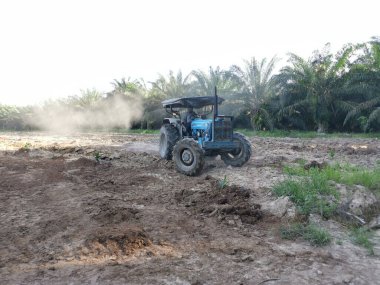 Traktörün boş araziyi sürdüğü sahne.
