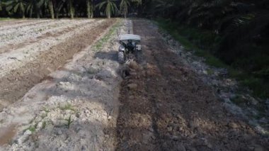 Perak, Malezya. 26 Mayıs 2022: Kampong Koh Özel Çiftliği 'nde traktörün boş tarım arazisini sürdüğü hava sahnesi.