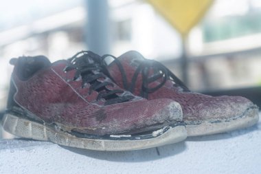 Ön verandadaki beton sütundaki yıpranmış spor ayakkabı.
