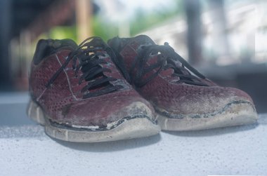Ön verandadaki beton sütundaki yıpranmış spor ayakkabı.