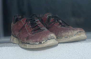 Ön verandadaki beton sütundaki yıpranmış spor ayakkabı.