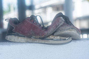 Ön verandadaki beton sütundaki yıpranmış spor ayakkabı.
