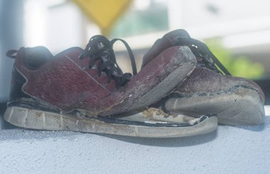 Ön verandadaki beton sütundaki yıpranmış spor ayakkabı.