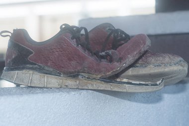 Ön verandadaki beton sütundaki yıpranmış spor ayakkabı.