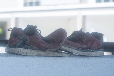Ön verandadaki beton sütundaki yıpranmış spor ayakkabı.