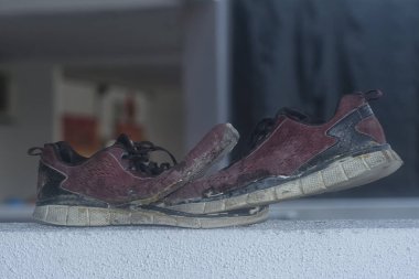 Ön verandadaki beton sütundaki yıpranmış spor ayakkabı.